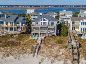 A beachfront property with multiple houses connected by a wooden boardwalk, featuring balconies and direct views of the ocean. - Carrle/Trachtman by Topsail Realty (Holly Ridge)