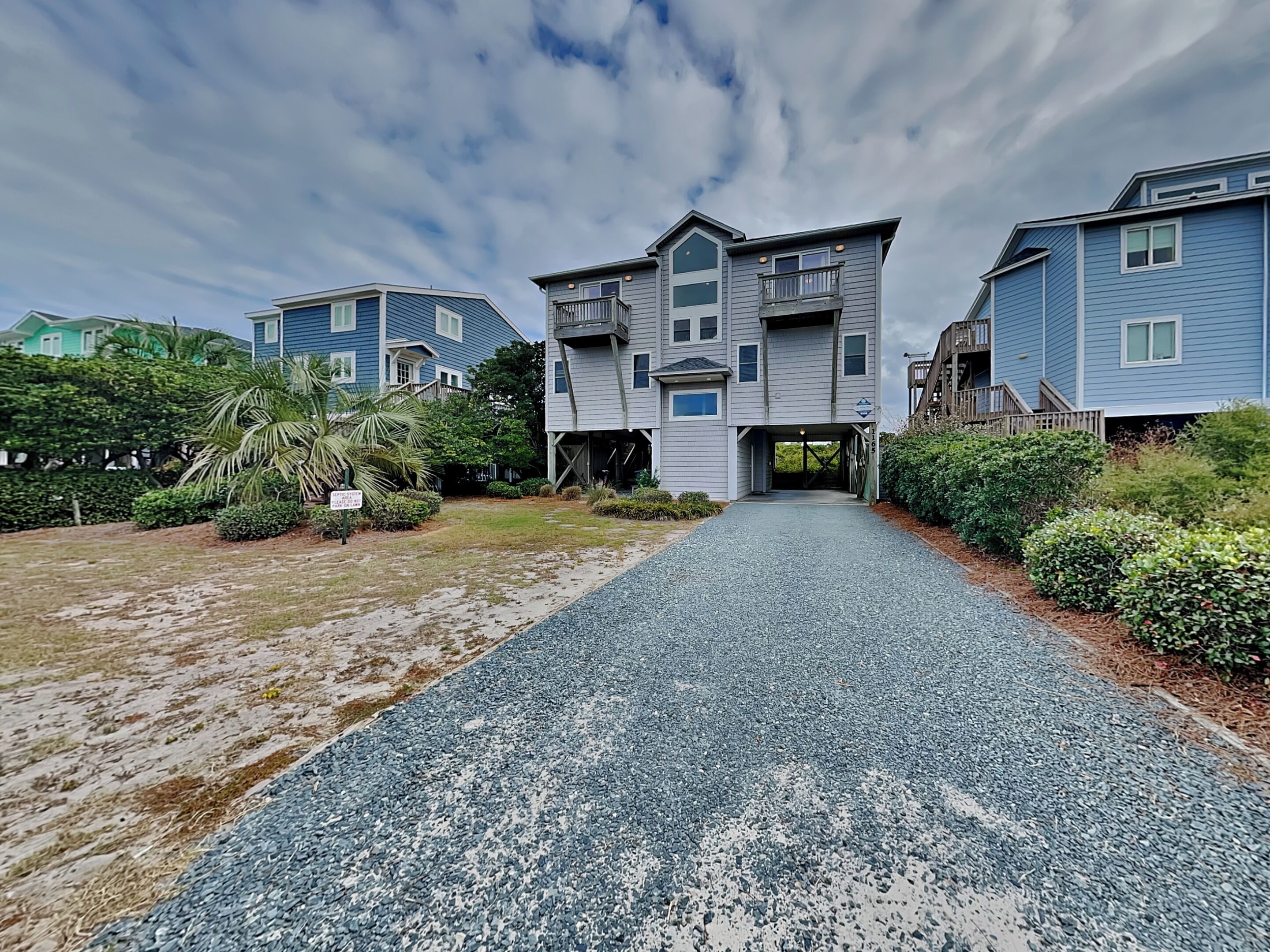 A residential building with a gravel driveway leading to a gated entrance.