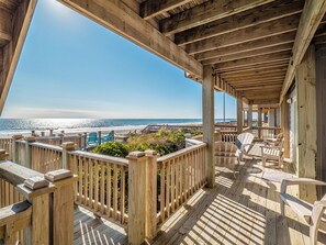 Una terraza de madera con vista a la playa y al océano.