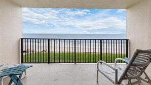 A balcony with a view of the beach, a table, and a chair. - Southwind 304 (New Smyrna Beach)