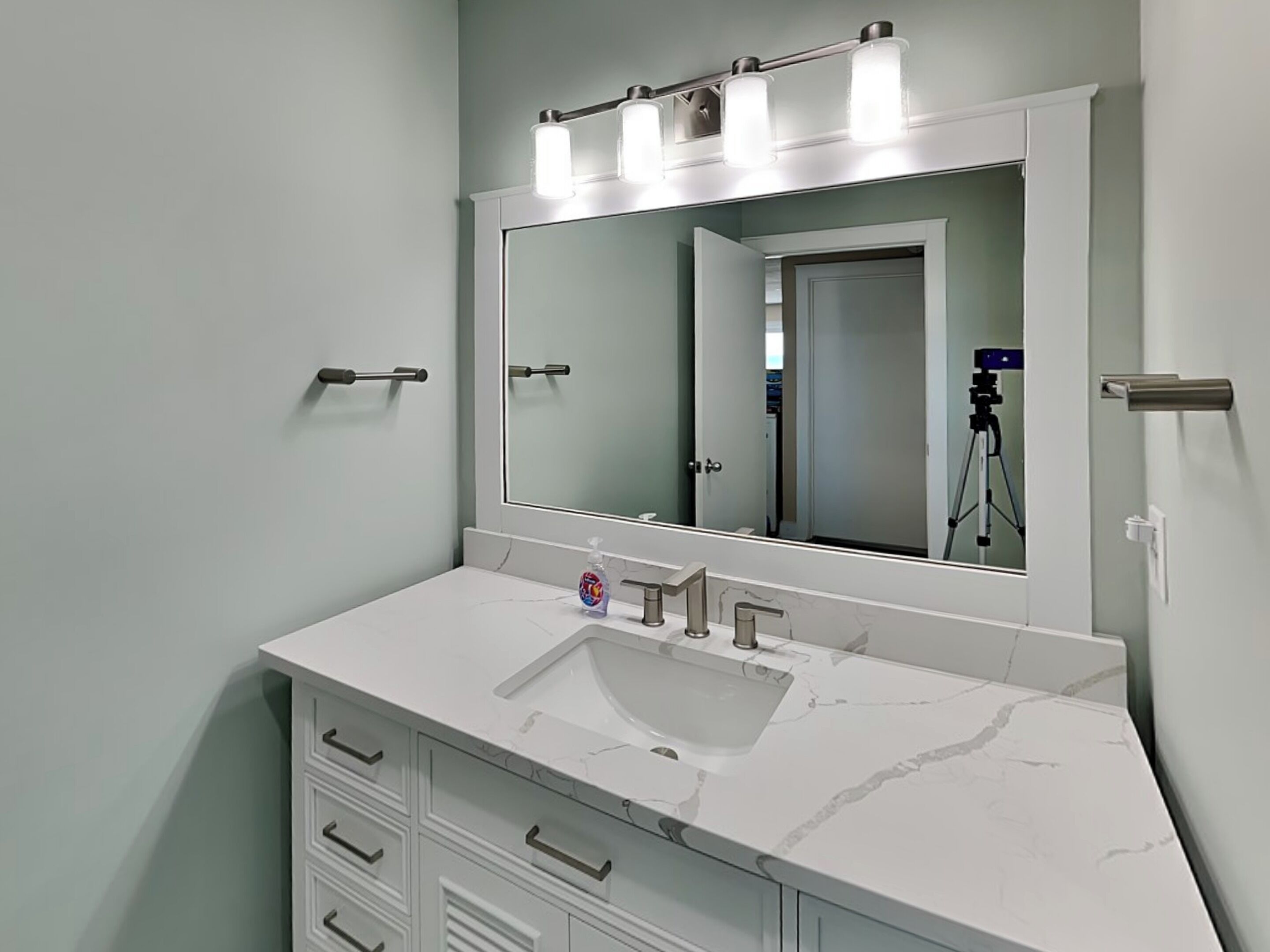 Un baño con tocador blanco, un espejo grande y un lavabo.