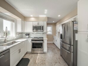 Enjoy cooking in this well-equipped kitchen with a stainless steel refrigerator, oven, and microwave, plus a convenient window with blinds.