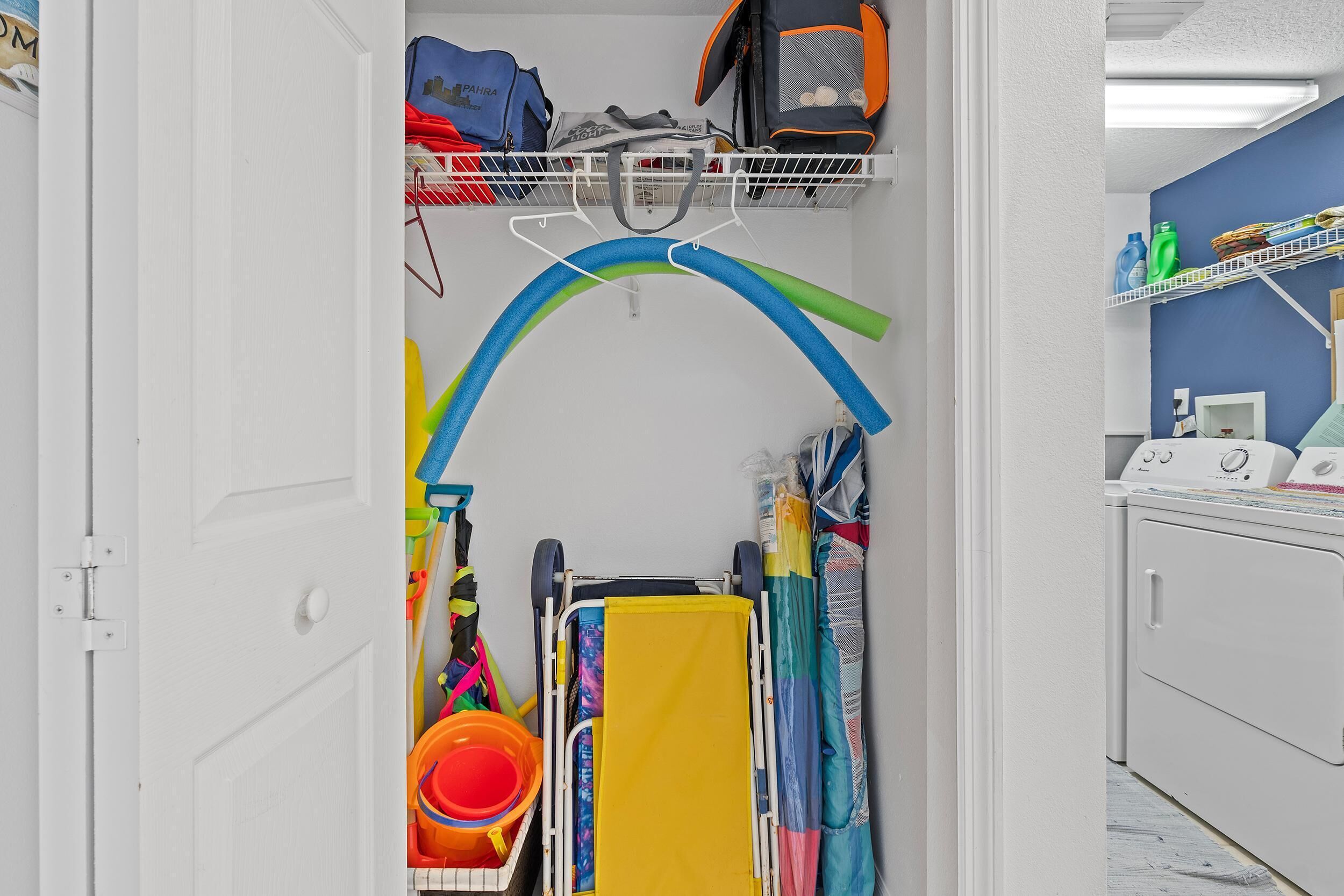 A laundry area with a cart, hanging laundry, and a shelf with cleaning supplies.