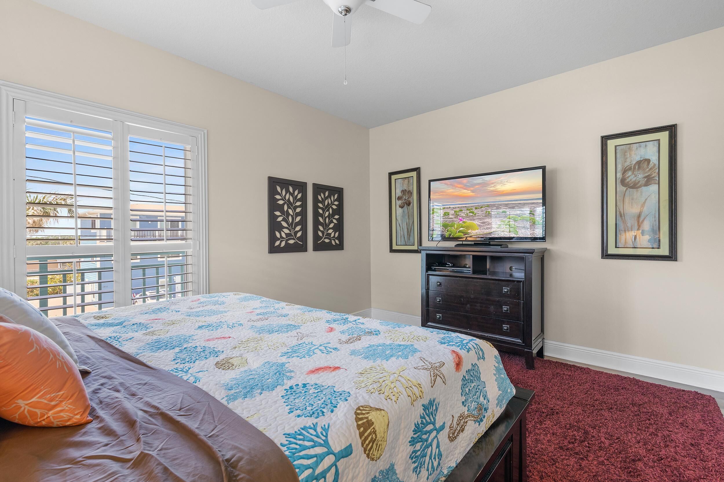 A bedroom with a bed, a dresser, a TV, and artwork on the walls.