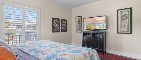 A bedroom with a bed, a dresser, a TV, and artwork on the walls.