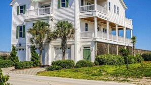 A two-story white house with green shutters, a balcony, and a covered porch. - Oceans 111 by Topsail Realty (Holly Ridge)