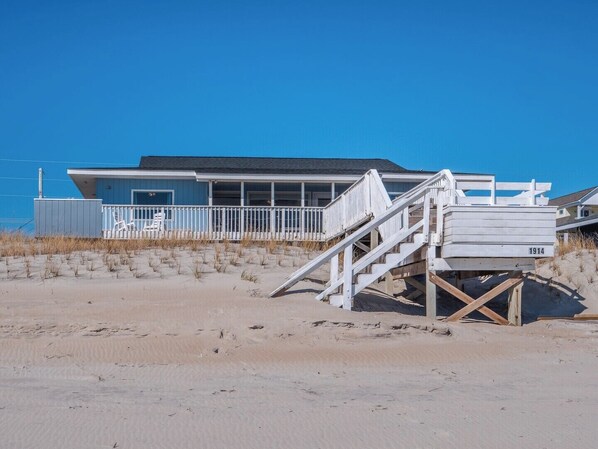 A beach house with a blue exterior, white railings, and a wooden staircase leading to a deck. - The Shark and the Seahorse by Topsail Realty (Holly Ridge)