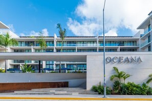 Un hotel moderno con un llamativo letrero 'OCEANA', una estructura de varios pisos y zonas de estar al aire libre.