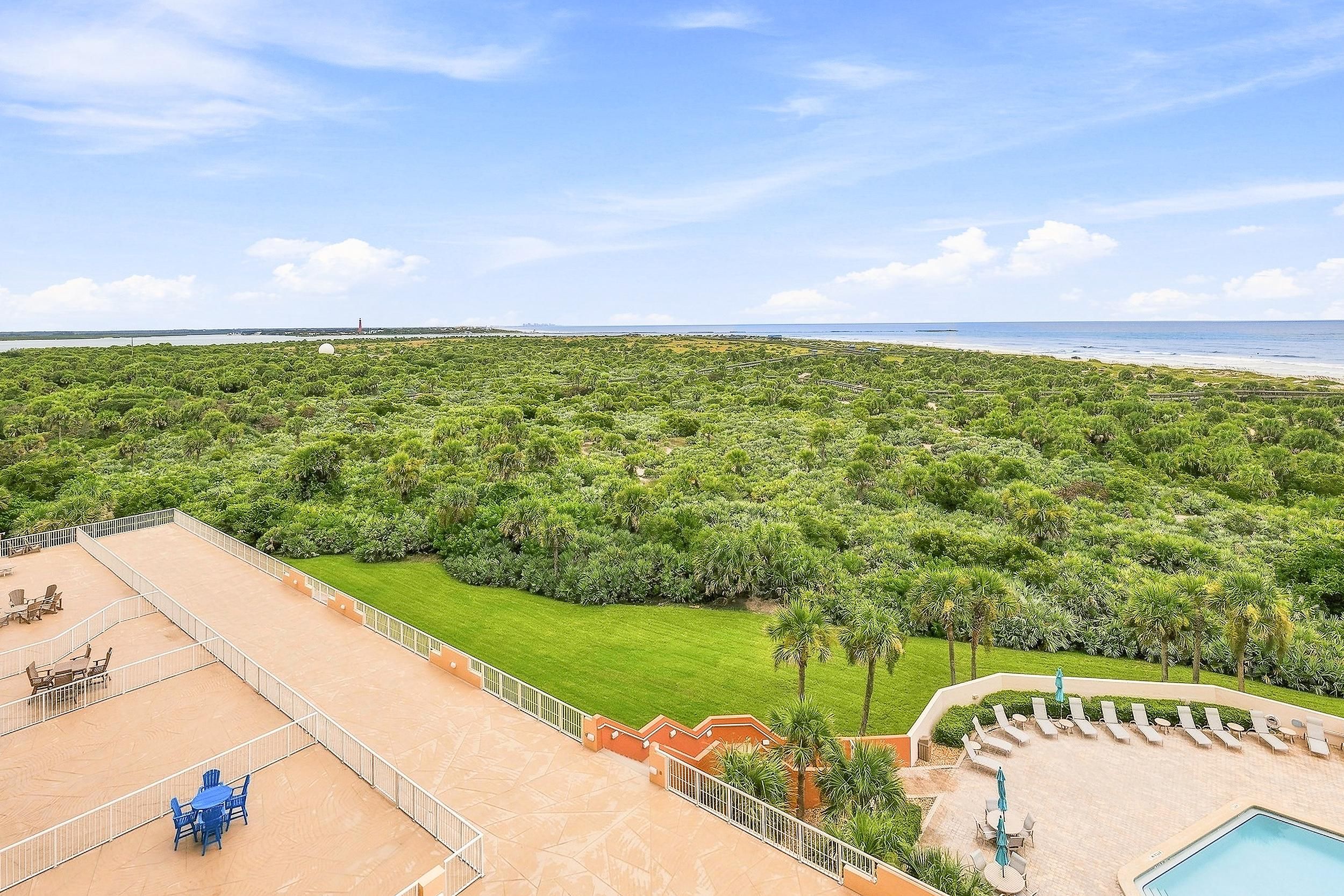 A resort with a pool area, lounge chairs, and a view of the ocean.