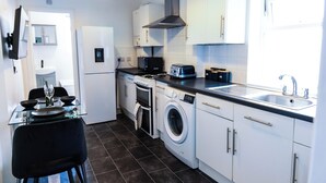 A compact kitchen with a washing machine, a microwave, a toaster, and a sink. - Charming Dartford Apartment - Ideal for Explorers! (Dartford)