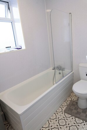 Une salle de bain avec une baignoire, une douche à parois de verre et des toilettes.