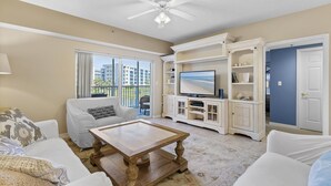 Ein Wohnzimmer mit Deckenventilator, Fernseher und Blick auf die Stadt.