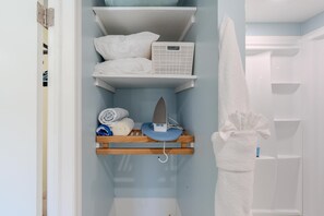 A bathroom with a shower, a towel rack, and a shelf with towels and a hairdryer. - Island Paradise 6 (Fort Myers Beach)