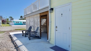 A building with a white door marked with the number 6, a covered porch with two Adirondack chairs, and a clear sky. - Island Paradise 6 (Fort Myers Beach)