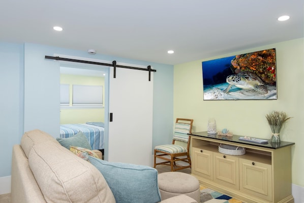 Una habitación con cama, una silla, un escritorio y un cuadro de una tortuga en la pared.