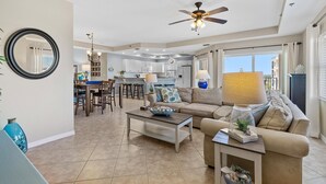 A spacious living room with a sofa, coffee table, and a dining area in the background. - Oceanwalk 8-507 (New Smyrna Beach)