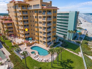 Un hotel de varios pisos con piscina, zona de estar al aire libre y vista a la playa.