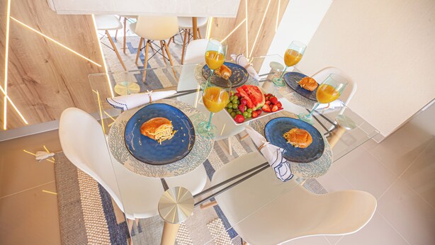 A dining table with plates, glasses, and a fruit arrangement. - Appart Nautic Piura (Piura)