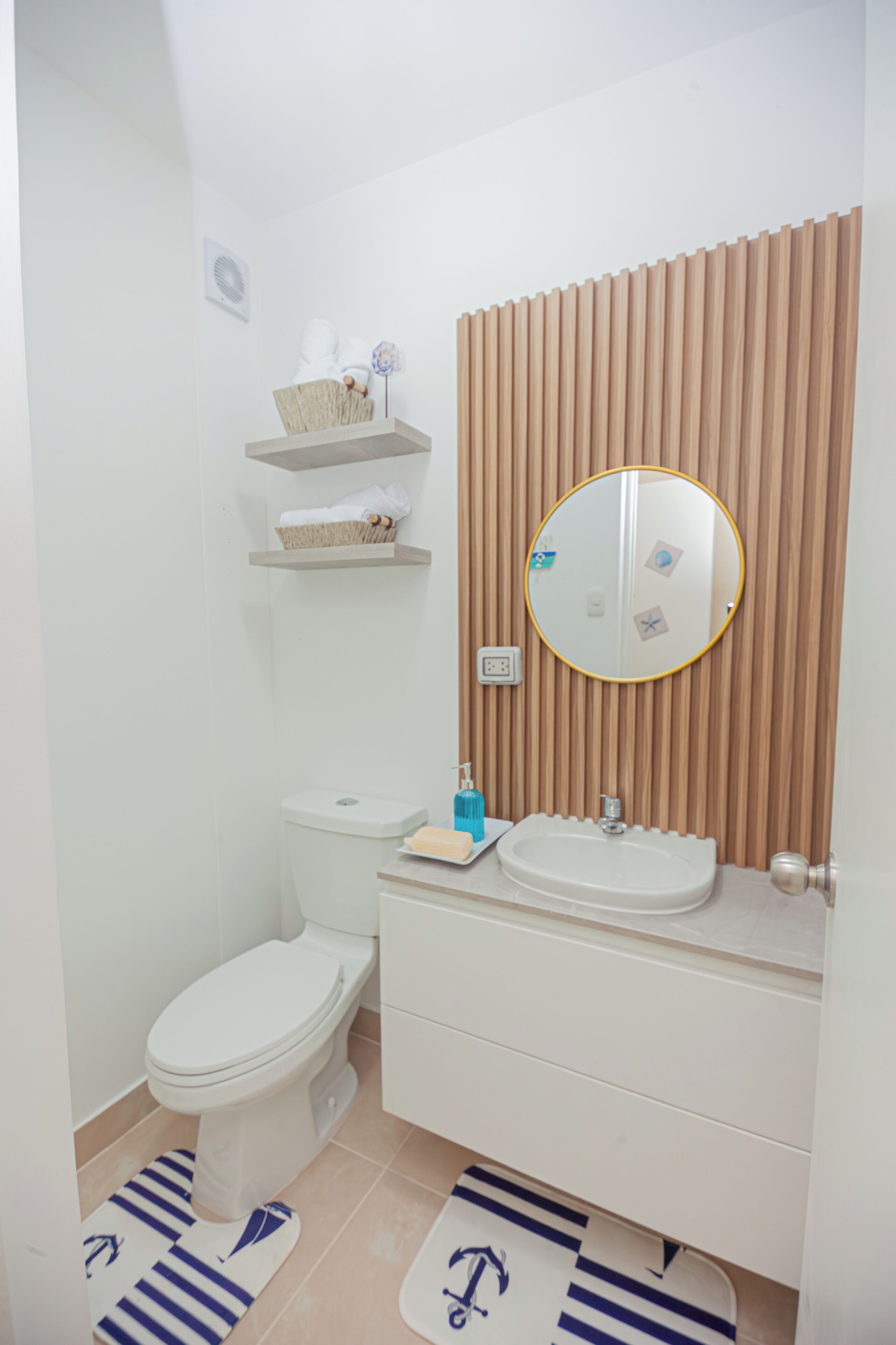 Ein Badezimmer mit Toilette, Waschbecken, Spiegel und Holzvertäfelung.