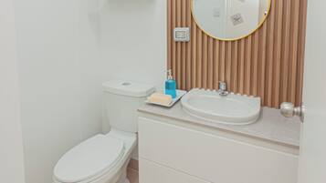 Ein Badezimmer mit Toilette, Waschbecken, Spiegel und Holzvertäfelung.