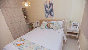 A bedroom with a bed, a nightstand, a dresser, and a wall with a seahorse painting. - Appart Nautic Piura (Piura)