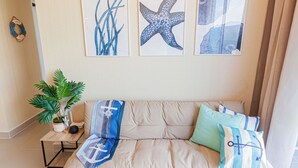 A living room with a beige sofa, a woven rug, and three framed artworks on the wall. - Appart Nautic Piura (Piura)