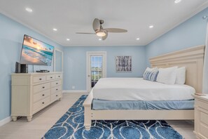 A bedroom with a bed, dresser, television, ceiling fan, and artwork. - Sea Club #25 - Dolphin's Watch (Indian Shores)