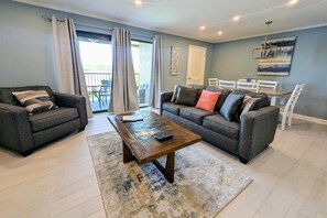 Relax in this spacious living room with a large window, dining area, and comfortable seating.