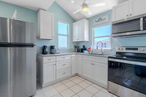 A modern kitchen with stainless steel appliances, white cabinetry, and a tiled floor. - Island Paradise 4 (Fort Myers Beach)