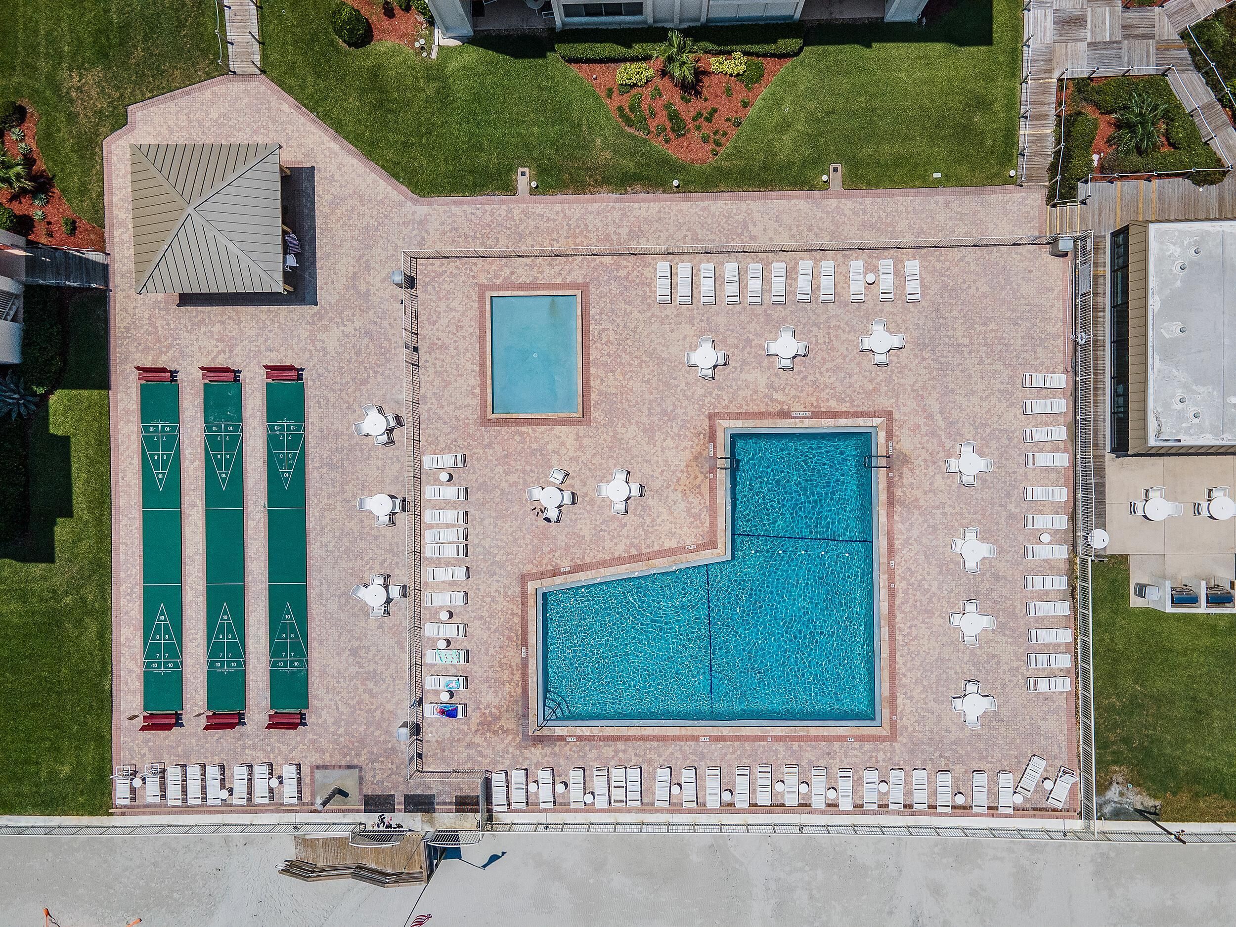 Vista aérea de un área de piscina con varias piscinas, tumbonas y una cancha de paletas.