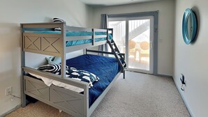 A bunk bed room with a view to an outdoor patio.