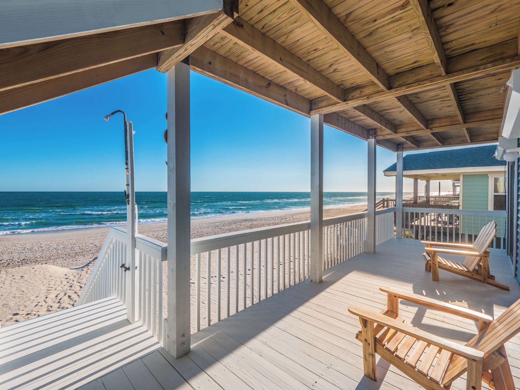 A wooden deck with a view of the beach and ocean.