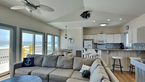 A modern living room with a sectional sofa, a dining table, and a kitchen area.