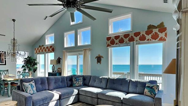 A spacious living room with a large L-shaped sectional sofa, a round coffee table, and a ceiling fan. - Clamalot by Topsail Realty (Holly Ridge)