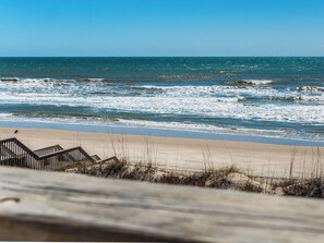 A beach with waves, a wooden fence, and a clear sky. - The Salty Spot by Topsail Realty (Holly Ridge)