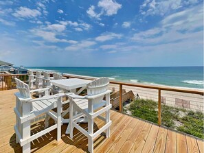 A deck with white chairs and tables overlooking a beach. - The Salty Spot by Topsail Realty (Holly Ridge)