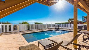 A pool area with a wooden pergola, white fence, and lounge chairs. - Ocean Dream (New Smyrna Beach)