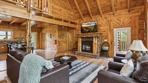 A log cabin interior with a fireplace, wooden walls, a dining area, and a cozy seating area. - Amazing Views Hot Tub Game Room Pool (Gatlinburg)