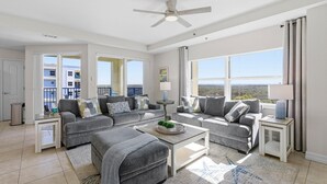 A spacious living room with grey sofas, a coffee table, and a ceiling fan.