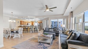 A spacious living area with a dining set, a gray sofa, and a ceiling fan.