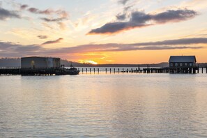 A pier extending into calm water with a sunset in the background.