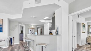Uma cozinha moderna com balcão, piso de madeira e vista para a sala de jantar.