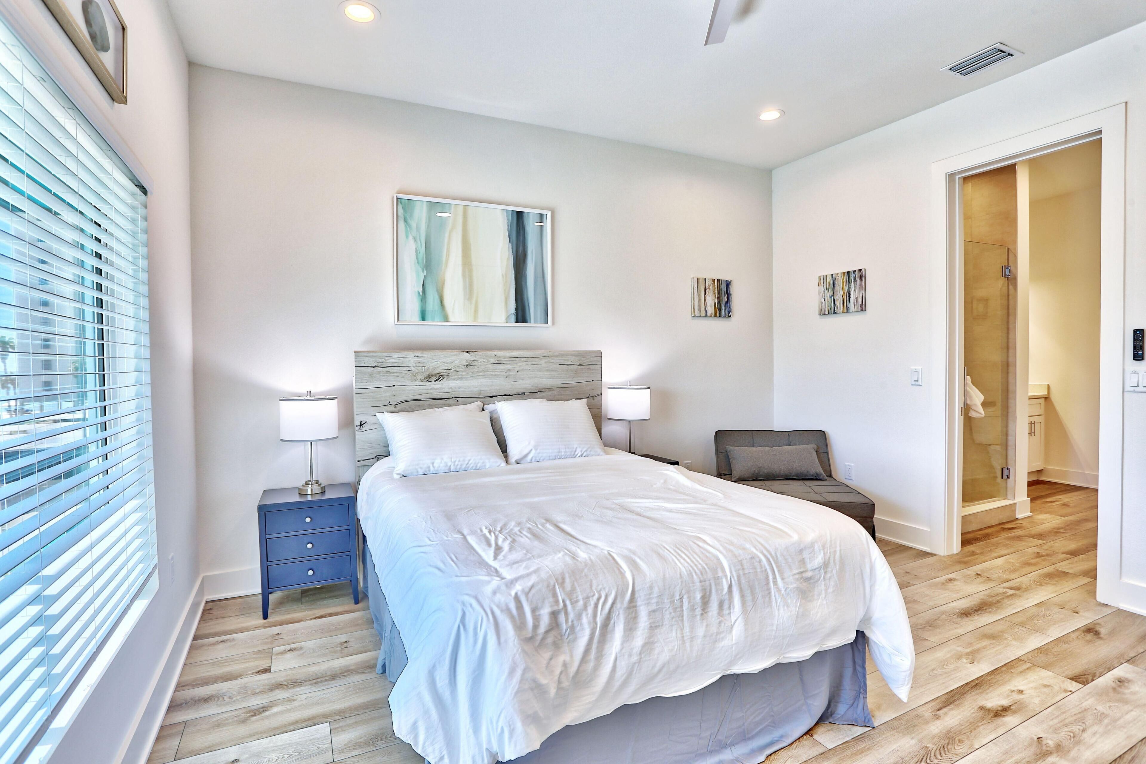Une chambre à coucher moderne avec un grand lit, des tables de chevet, une chaise et un dressing.