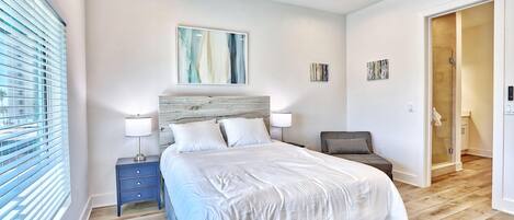 Une chambre à coucher moderne avec un grand lit, des tables de chevet, une chaise et un dressing.