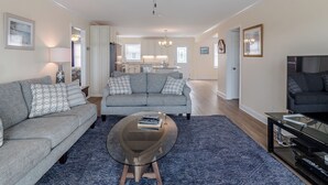 A spacious living room with a grey sofa, a coffee table, and a ceiling fan. - Bear's Den by Topsail Realty (Holly Ridge)