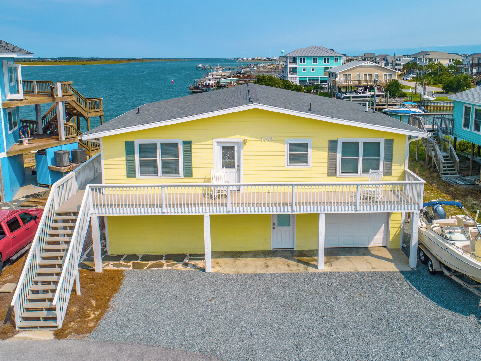 A yellow house with a balcony, a dock, and a boat.