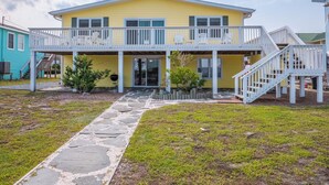 A yellow house with a covered porch and a stone pathway leading to the entrance. - Bear's Den by Topsail Realty (Holly Ridge)