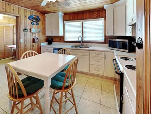 A compact kitchen with wooden cabinets, a white countertop, a microwave, and a stove. - Whitaker Sea La Vie by Topsail Realty (Holly Ridge)