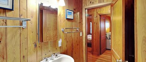 A wooden-paneled bathroom with a white sink, a towel rack, and a framed picture on the wall.