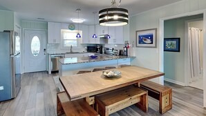 Une cuisine moderne dotée d’un îlot central, de bancs en bois et de luminaires suspendus.